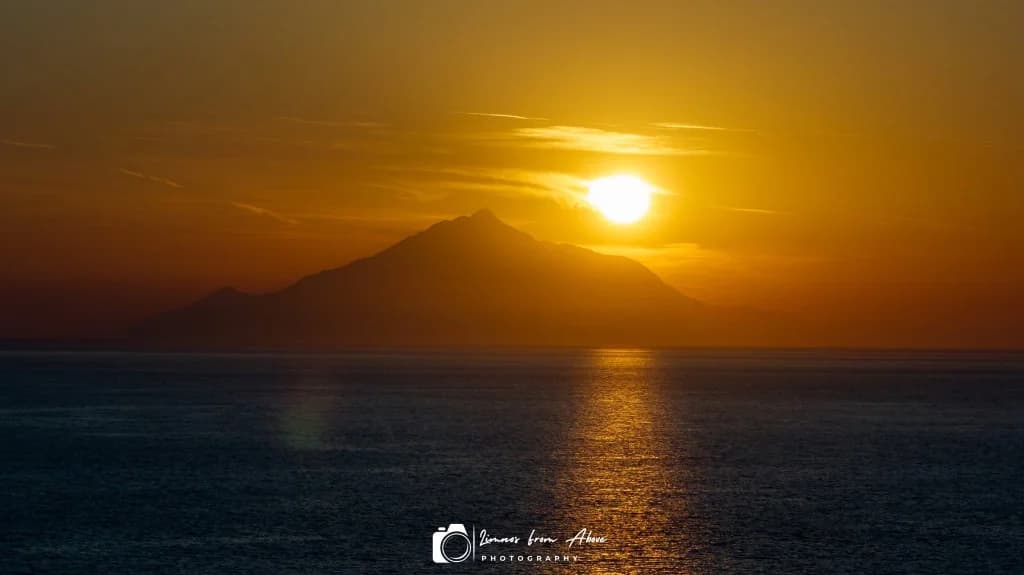 Rocky coastline at sunset with mountains on the horizon